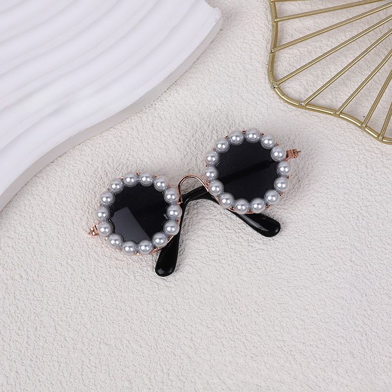Pearl sunglasses accessory with dark lenses, close-up on fabric