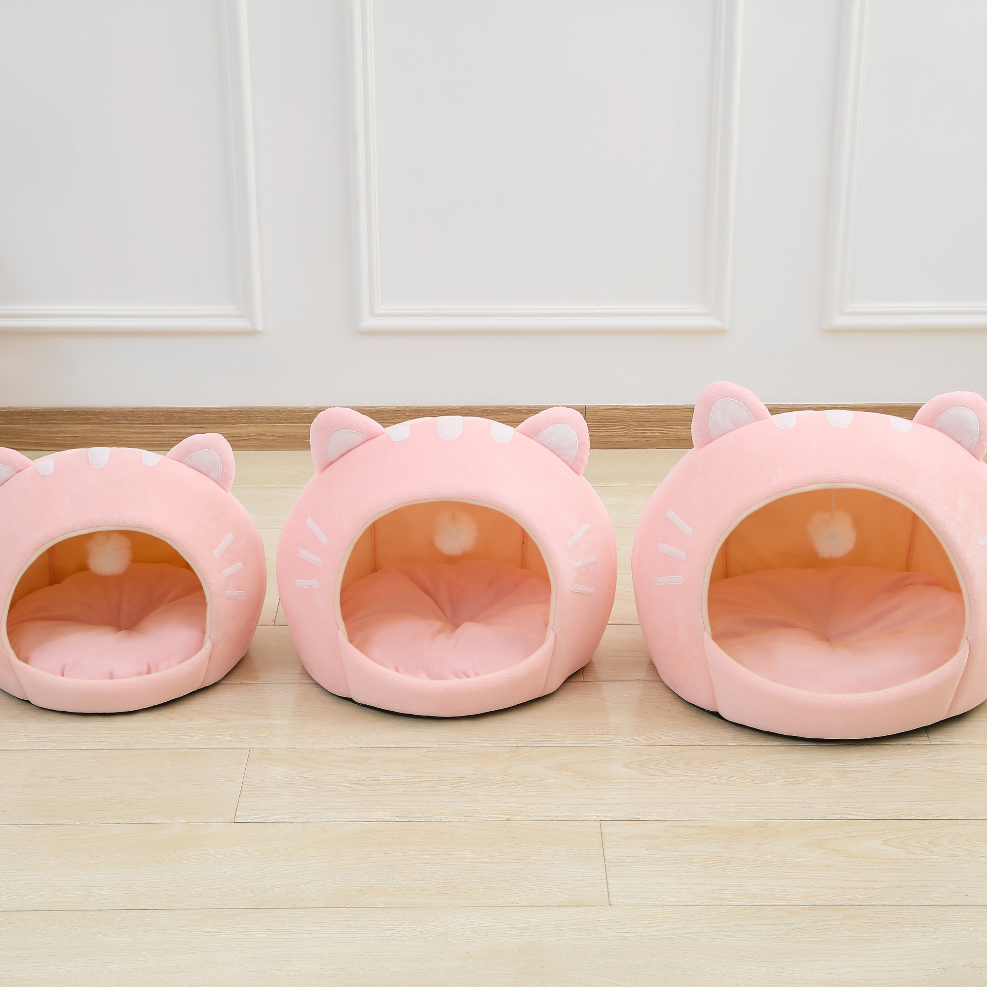 Three pink cat-shaped plush pet beds with round open entrances and ear hoods