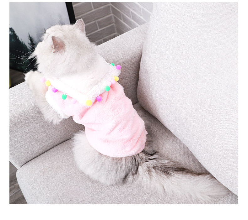 Lightweight pink pet hoodie on a seated cat, lace trim and pom-pom garland