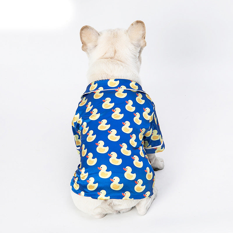 Dog wearing blue duck-print pet jacket with short sleeves and button front