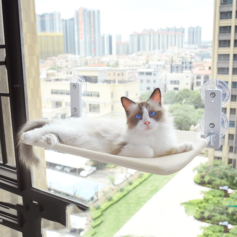 White-and-brown cat resting on beige mesh window hammock with suction cup mounts