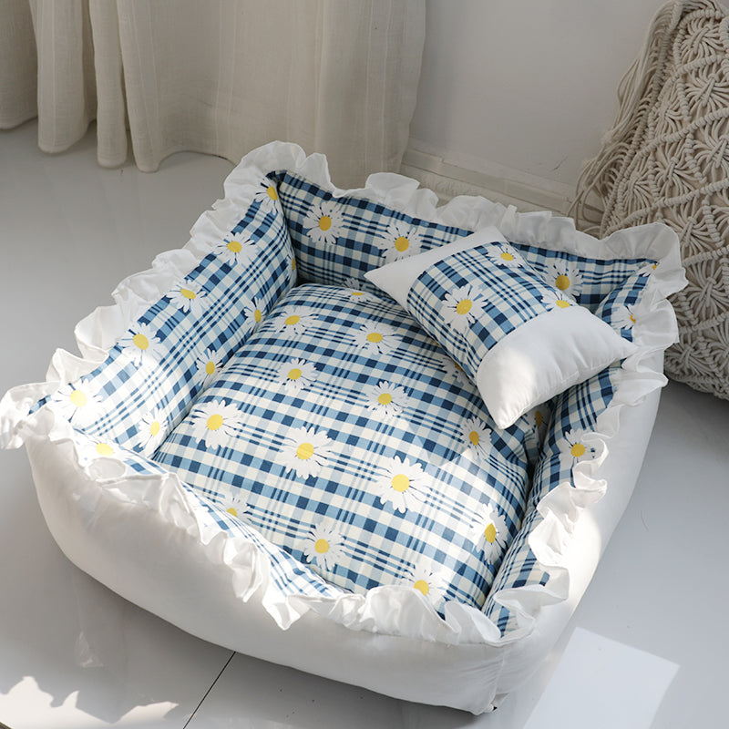 Blue plaid pet sofa bed cover with daisy pattern and white plush bolsters.