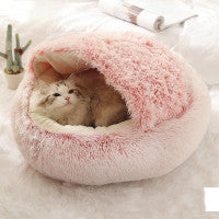 Round plush pet bed with pink fuzzy outer ring and covered sleeping cave opening