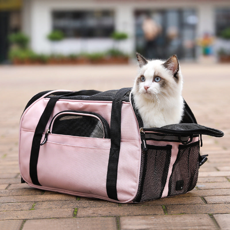 Pink pet carrier bag with mesh end panel and zip closures, pet seated inside