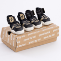 Kai- Dog sneakers in black with Velcro closures and tan accents on a shoebox