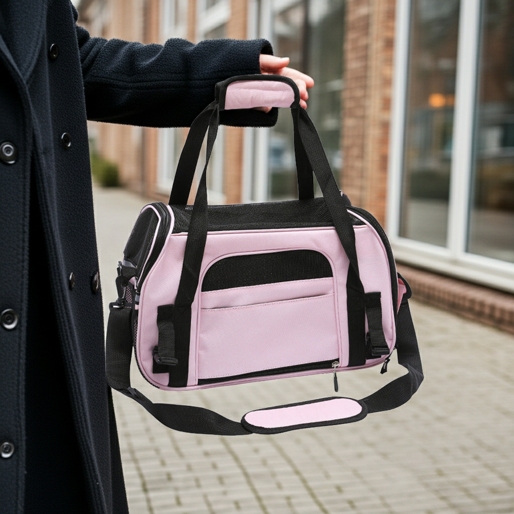 Pink pet carrier bag with black straps, front zip pocket, and carry handle