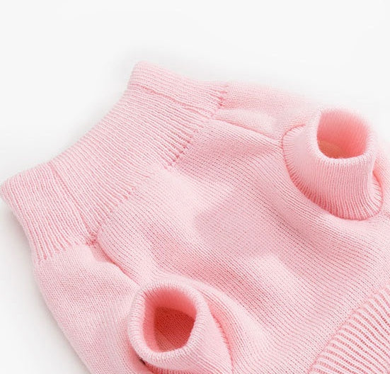 Pink knit pet sweater laid flat with ribbed collar and cutout armholes