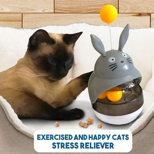 Gray bunny treat dispenser toy with hanging ball and clear compartment holding orange balls