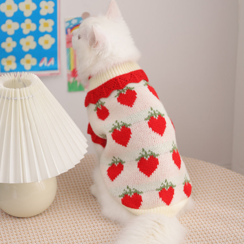 Cream knit cat sweater with red heart pattern and green accents