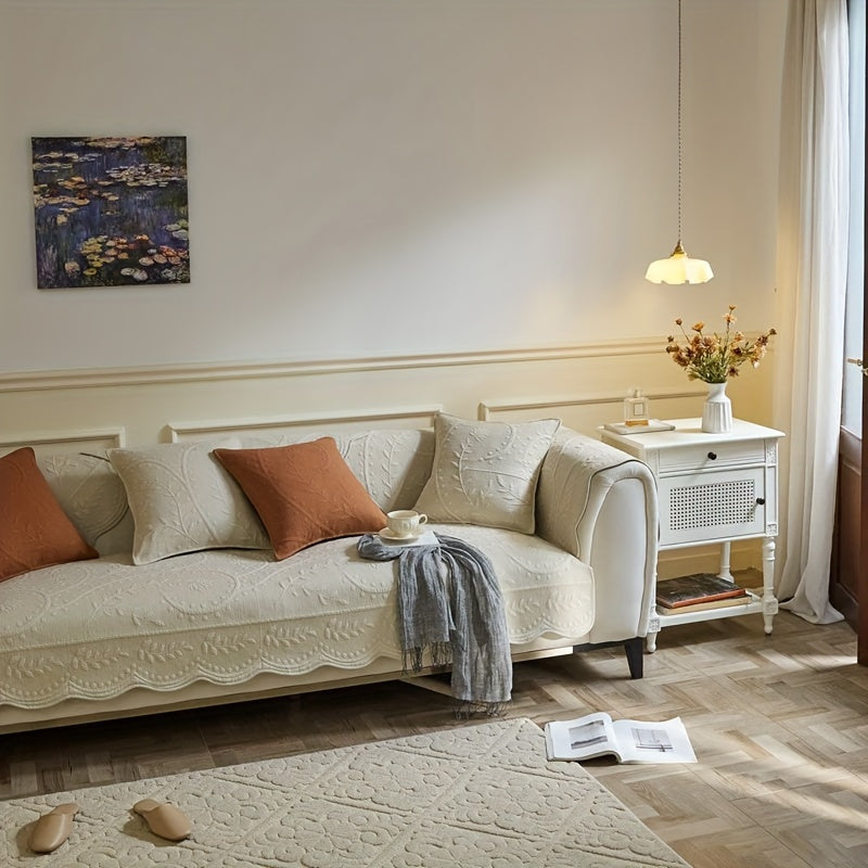 White waterproof sofa cover with scalloped edge over three-seat sofa and cushions