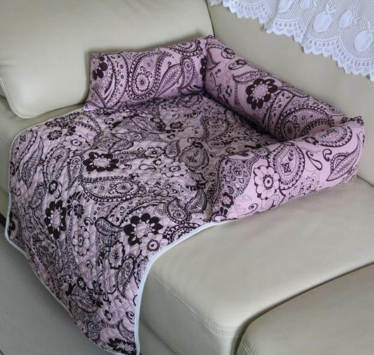 Lilac paisley floral cat bed with rolled side bolsters on a sofa seat
