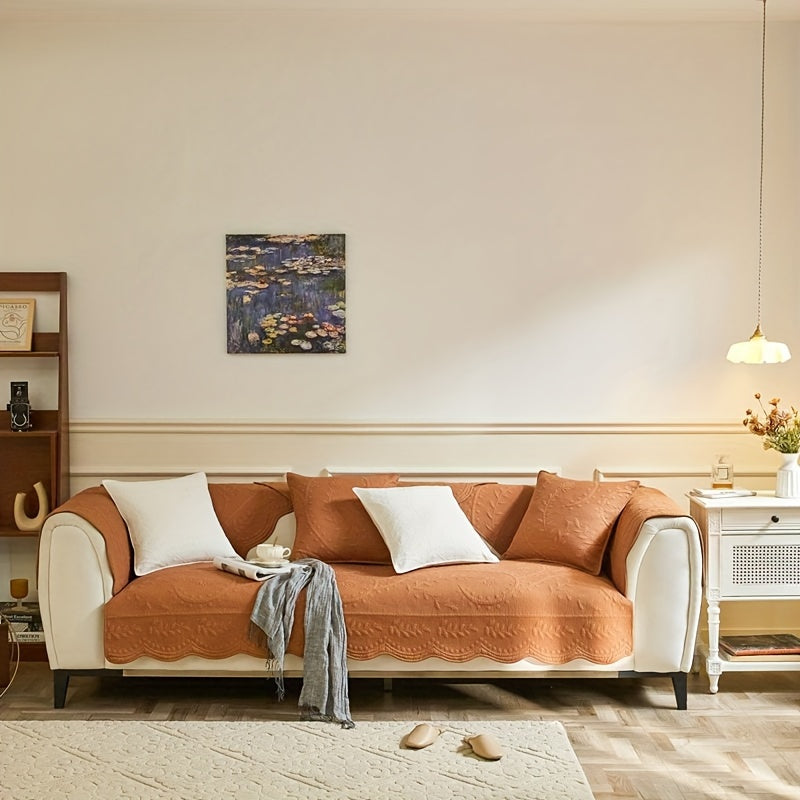 Tangerine/orange waterproof sofa cover draped over three-seat sofa with scalloped hem