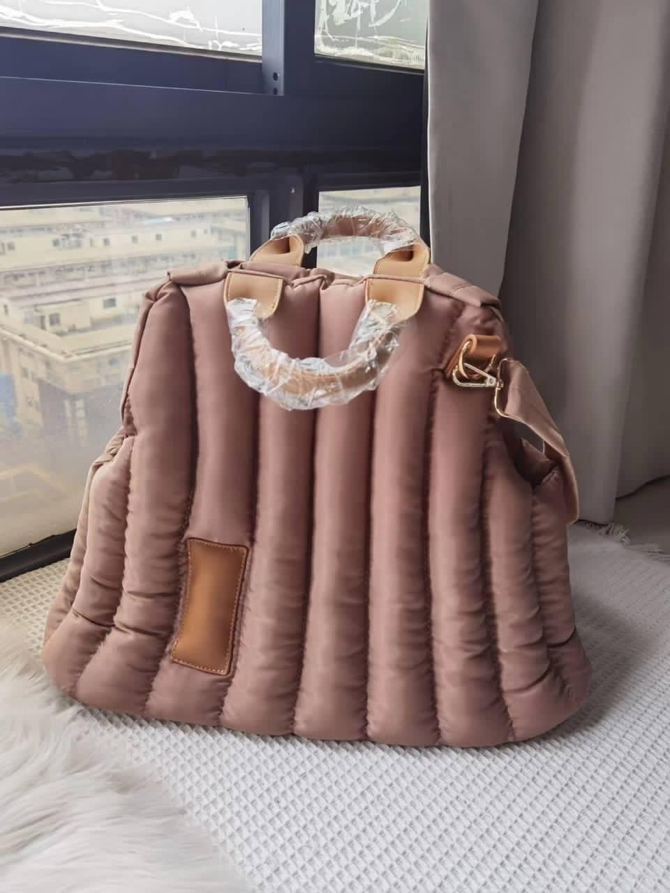 Blush quilted pet shoulder bag with tan handle straps and fleece-lined opening