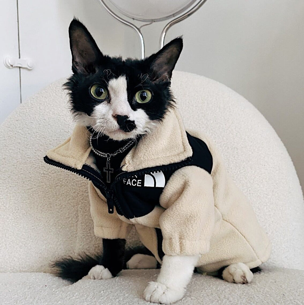 Cream and black sherpa cat jacket with zipper and hood, 'THE CAT FACE' chest patch.