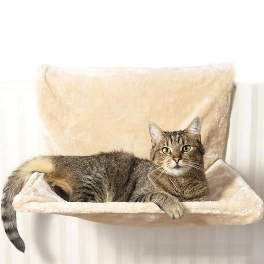 Tabby cat resting in beige plush cat bed with tall back cushion on a radiator