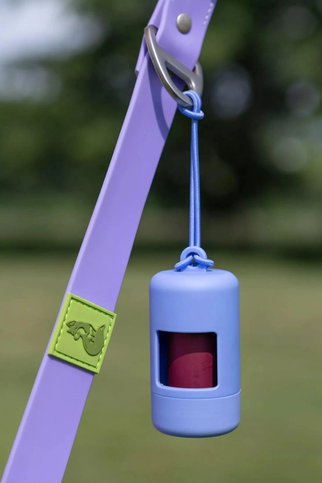 Cornflower blue waste bag dispenser hanging from lanyard with burgundy bag window