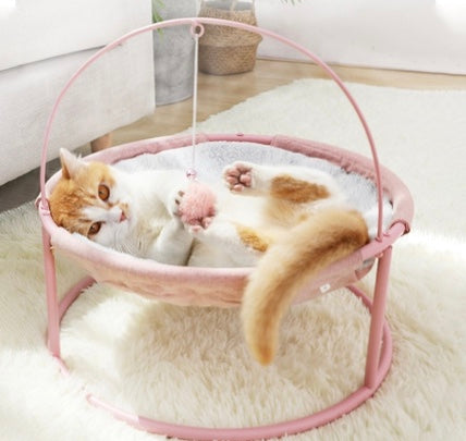 Pink-framed round pet bed with grey plush insert; curled cat resting inside