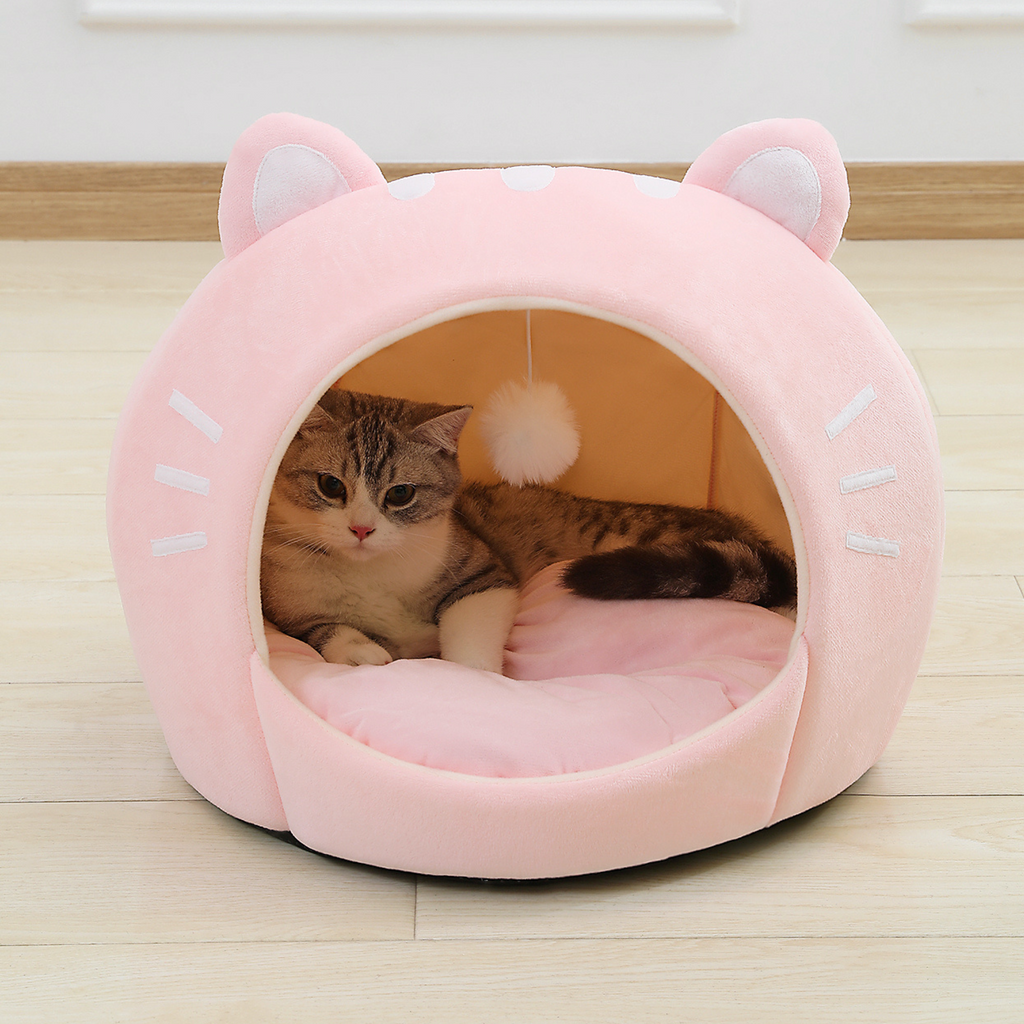 Pink cat-shaped plush pet bed with open entrance and ear hood, tabby cat inside