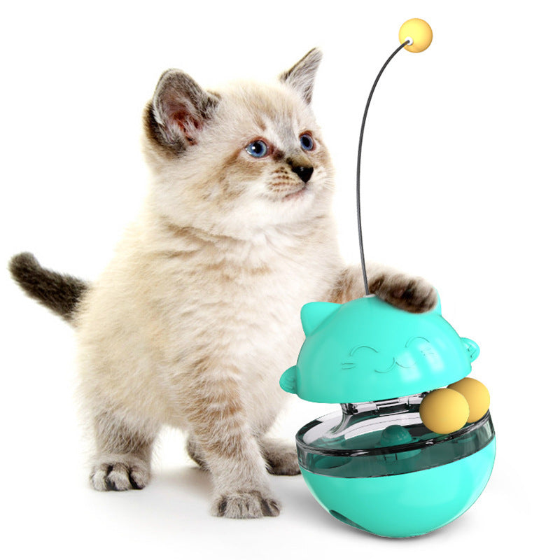Teal cat treat dispenser toy with clear bowl, yellow balls, and cat using it