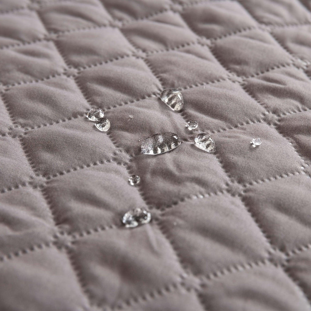 Close-up of quilted pet sofa cover fabric with stitched diamond pattern and silver snaps