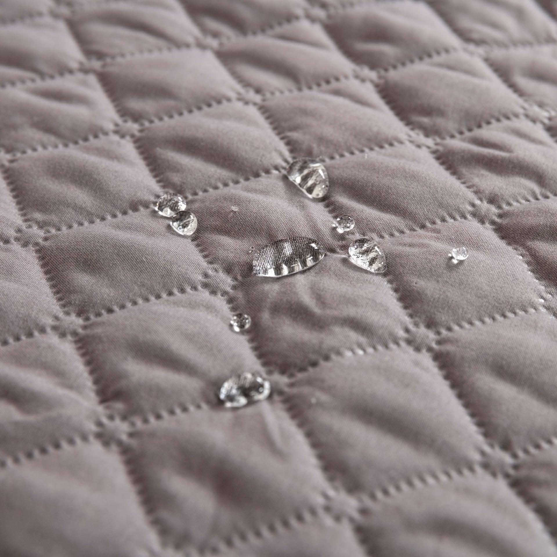 Close-up of quilted pet sofa cover fabric with stitched diamond pattern and silver snaps
