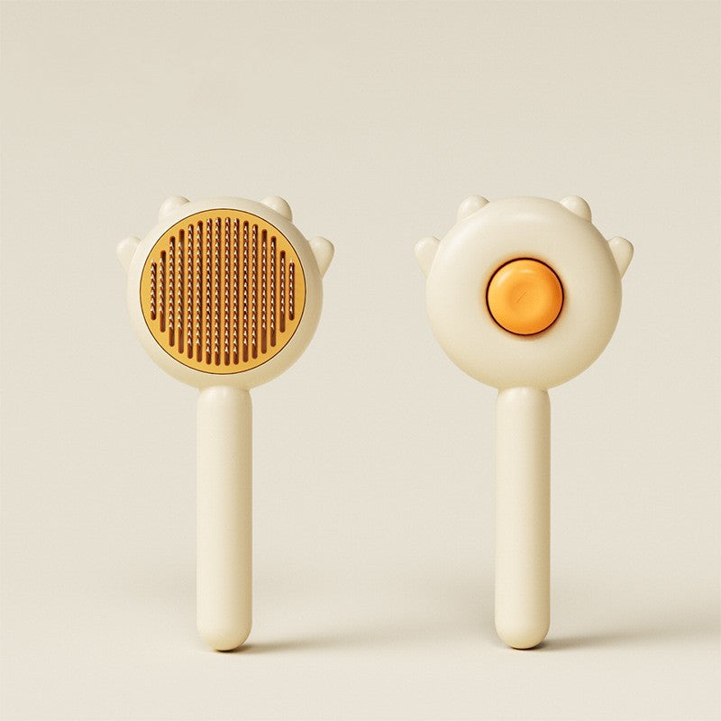 Pet grooming brush set with tan bristle oval head and orange button center on cream handles
