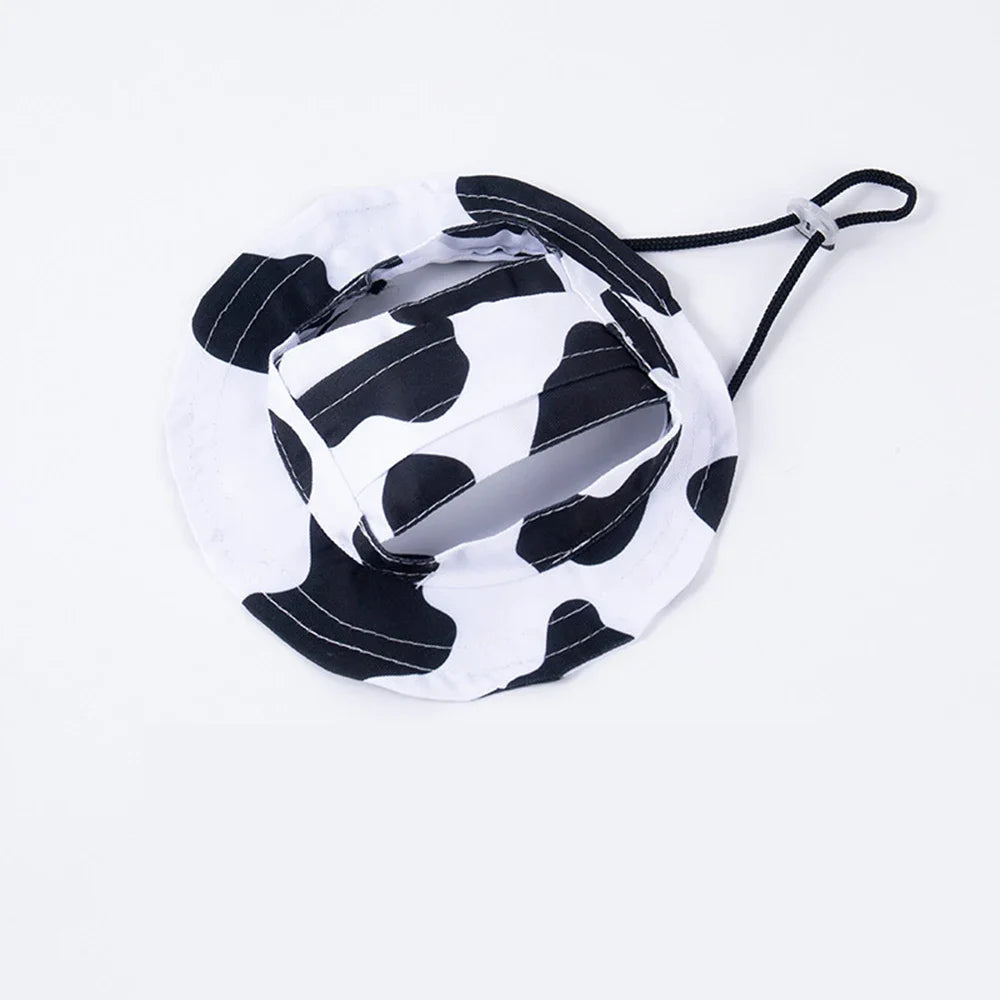 Adjustable pet bucket sun hat in black and white cow-print with chin strap and ear-hole openings