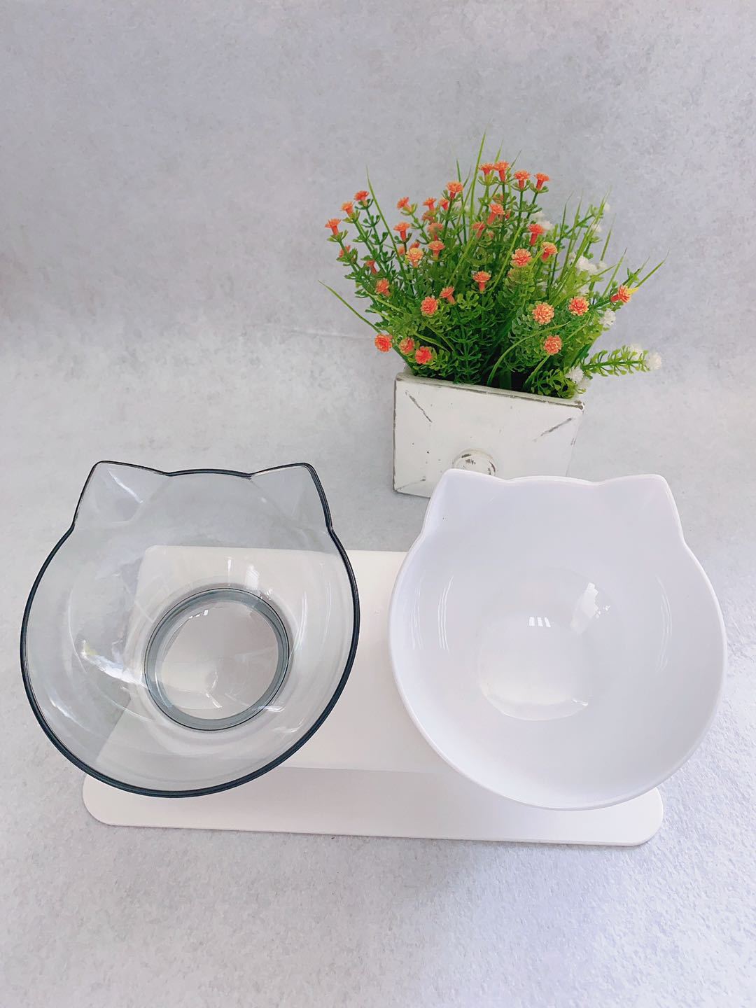 Double raised pet food bowls: clear and white cat-shaped dishes on white stand