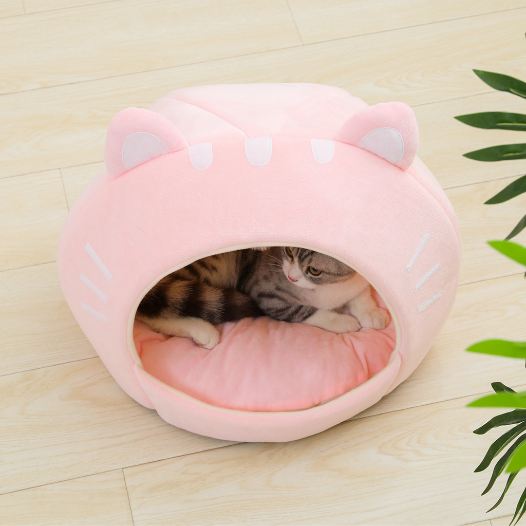 Pink cat-shaped plush pet bed with open entrance and ear hood, kitten inside