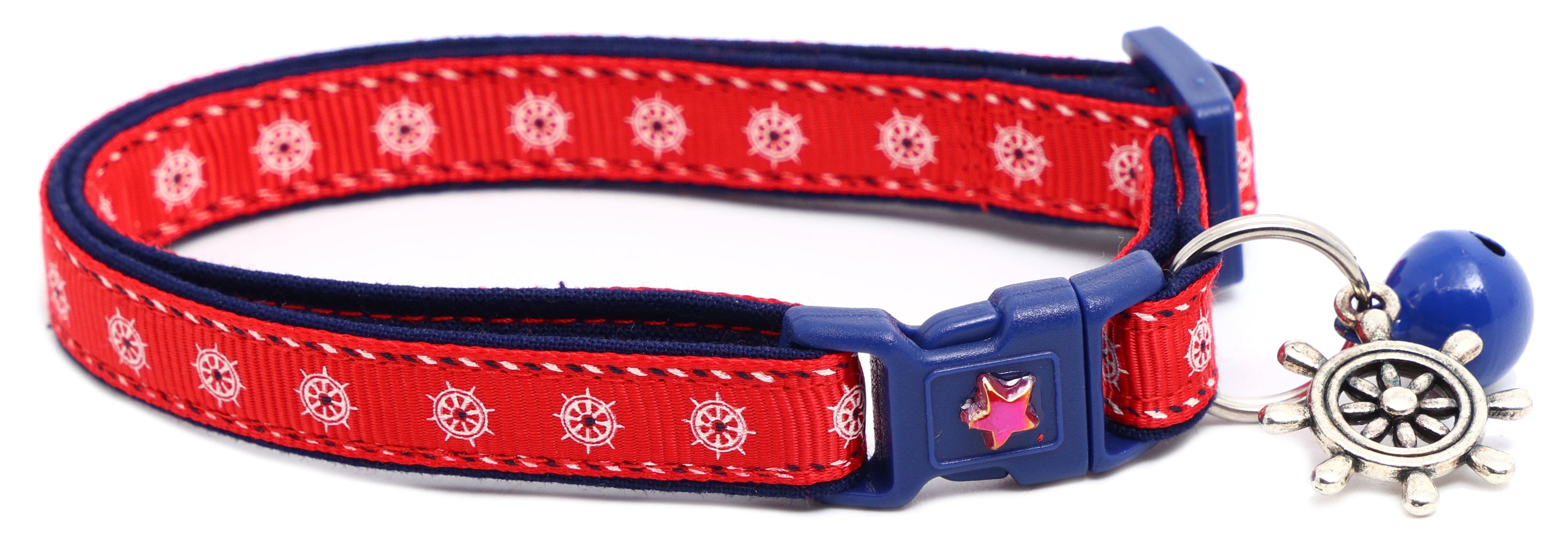 Red and navy cat collar with star charm, blue buckle, and small ship wheel charm