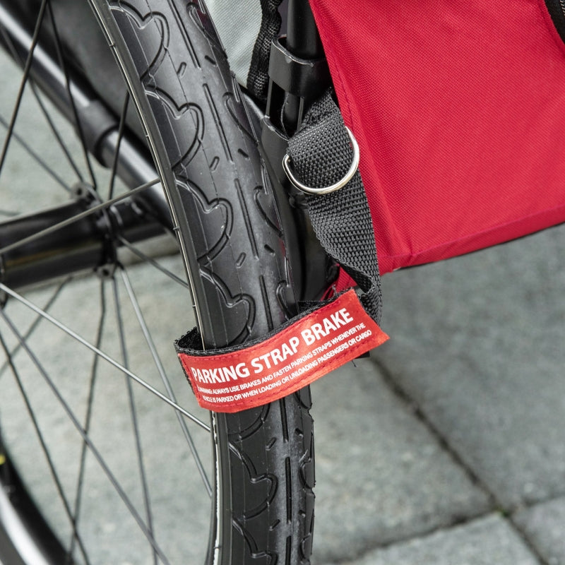 Parking strap brake on black wheel of red pet trailer