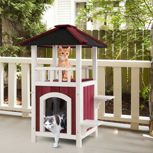 Two-story wooden cat house with white frame, red siding, black asphalt roof, balcony