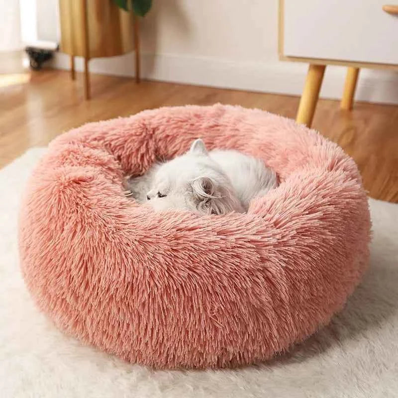 Pink donut pet bed plush nest with a white dog curled inside, shaggy texture