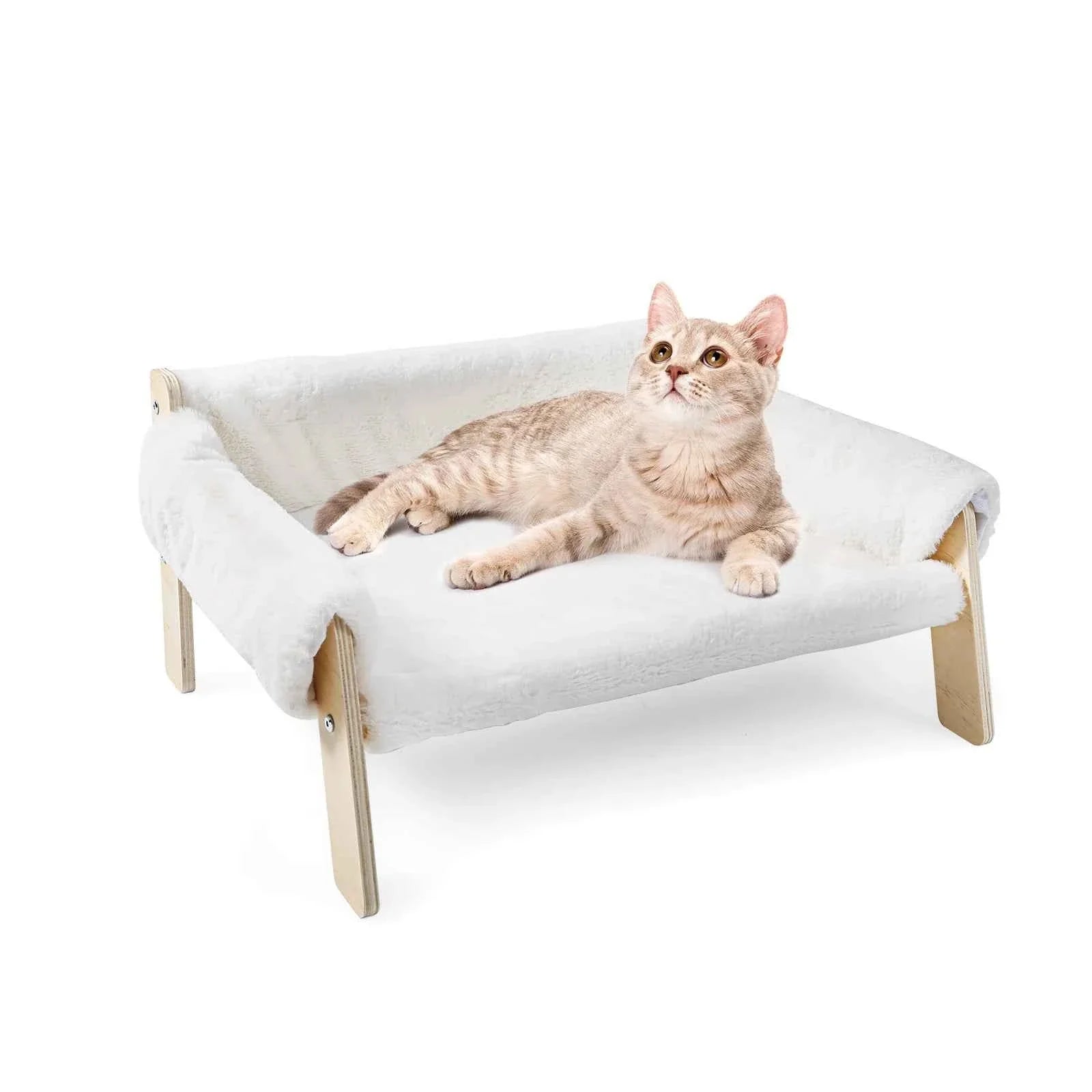 White plush raised cat sofa bed with wooden legs; light-colored cat resting on cushion