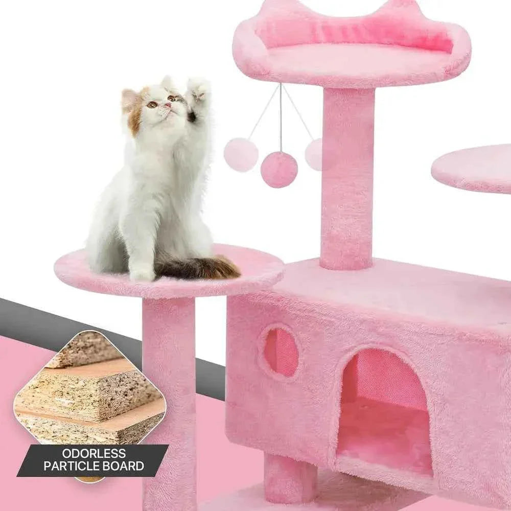 Pink cat tree platforms with hanging pom toys and arched cave opening; white cat