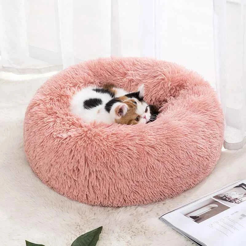 Pink donut pet bed with a cat curled inside; shaggy plush round nest