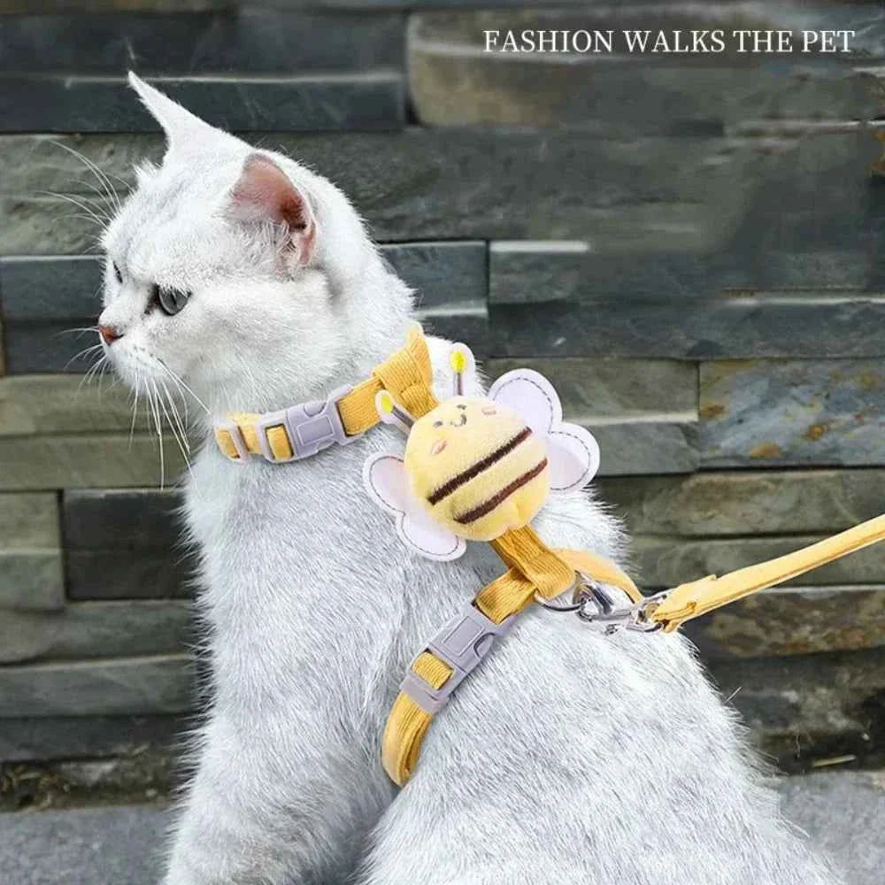 White cat wearing a yellow bee cat harness with adjustable buckle and leash