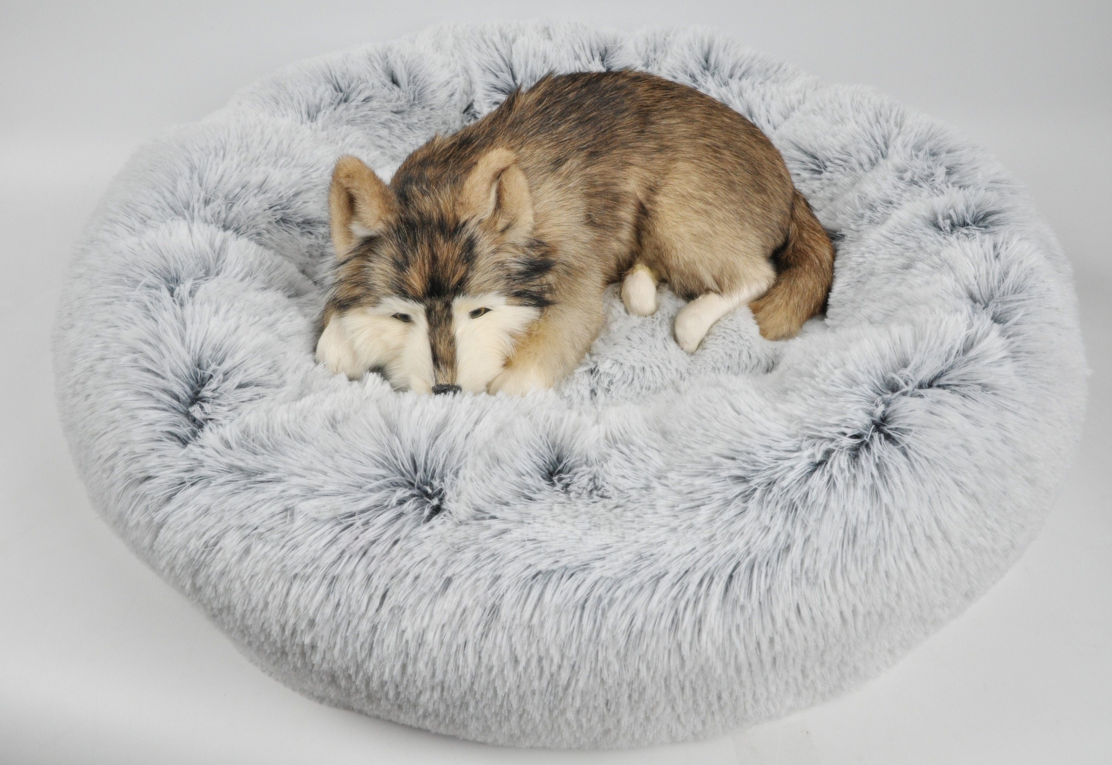 Round light gray plush pet bed with dog sleeping inside, paws tucked on the rim