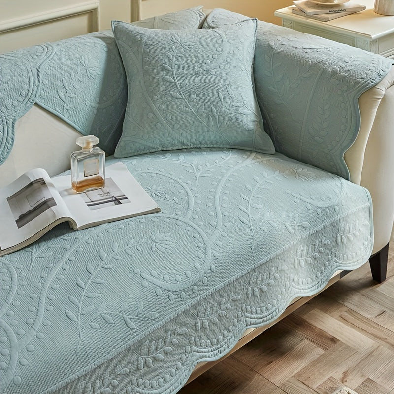 Light blue waterproof sofa cover with textured quilt pattern and scalloped side edge