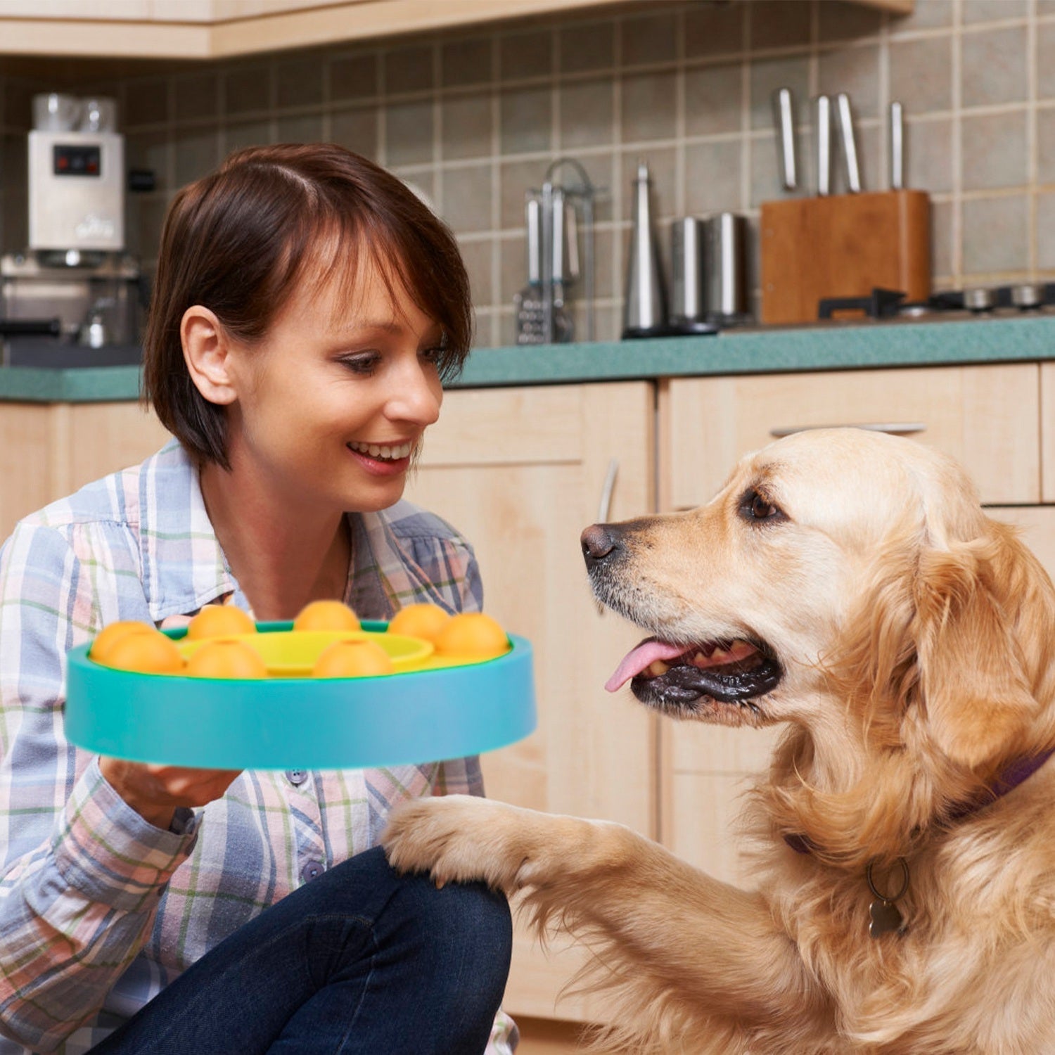 Slow feeding puzzle dog bowl with yellow interior and orange treat pods, teal outer ring