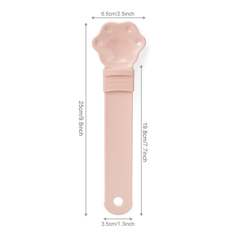 Pink cat treat squeeze spoon with paw-shaped tip and grip handle, front view