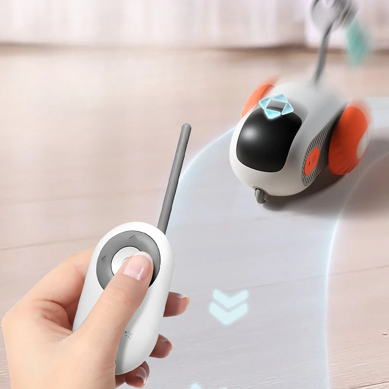 White remote-control cat car toy with orange bumper, shown with handheld remote
