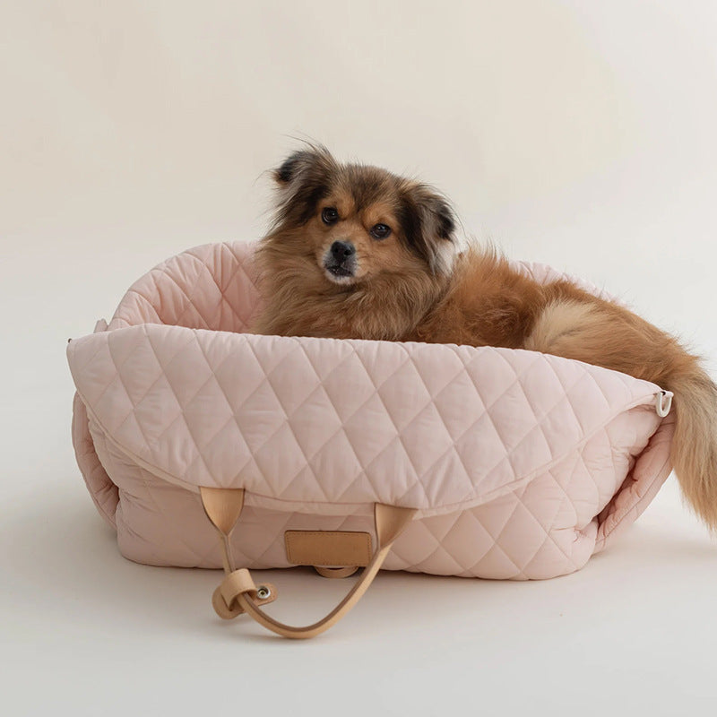 Pink quilted pet handbag with pet inside and side handle strap