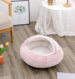 Round pink plush pet bed with thick cushioned rim and open sleeping center