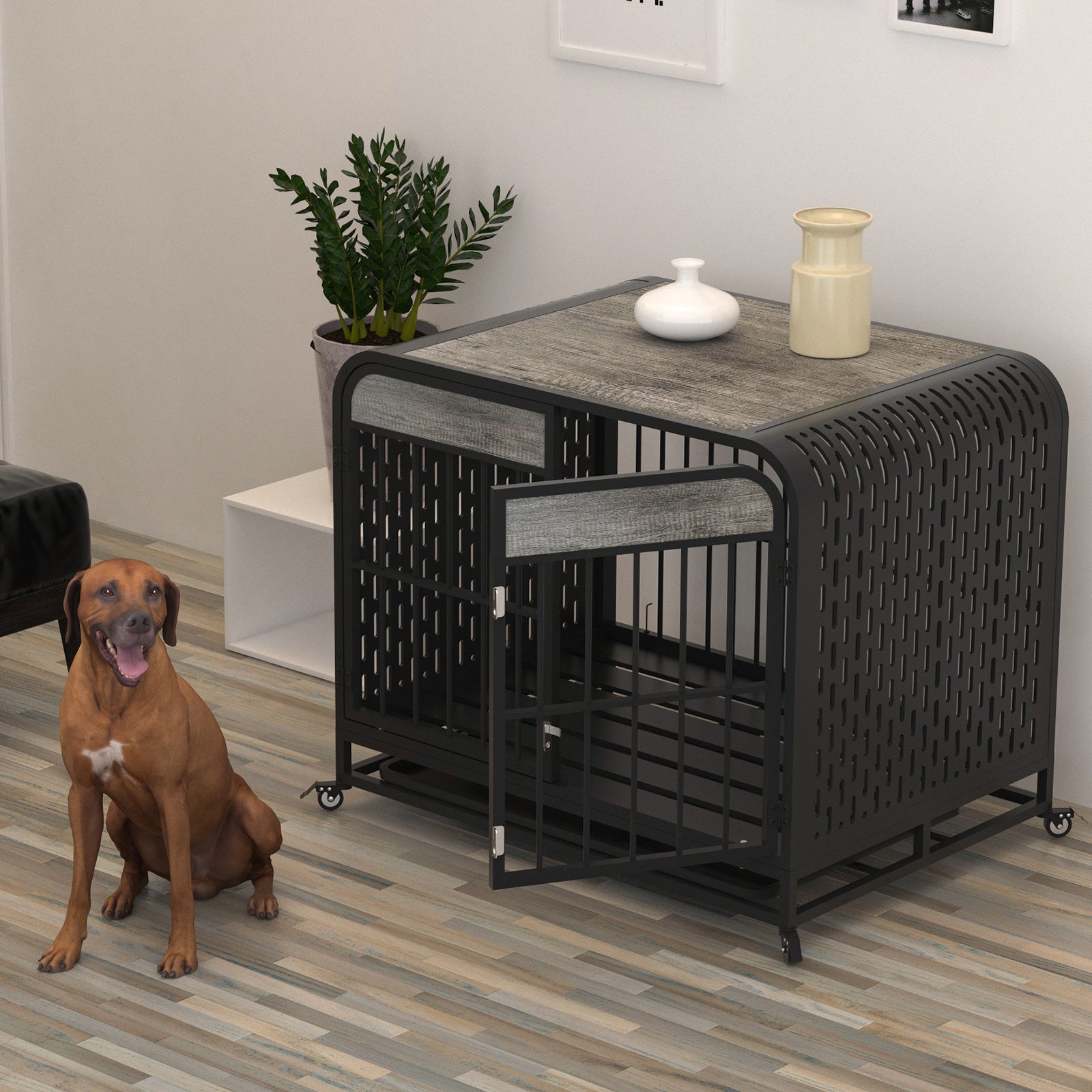 Grey dog crate table with steel-bar front door, perforated side panels, rolling wheels; brown dog nearby