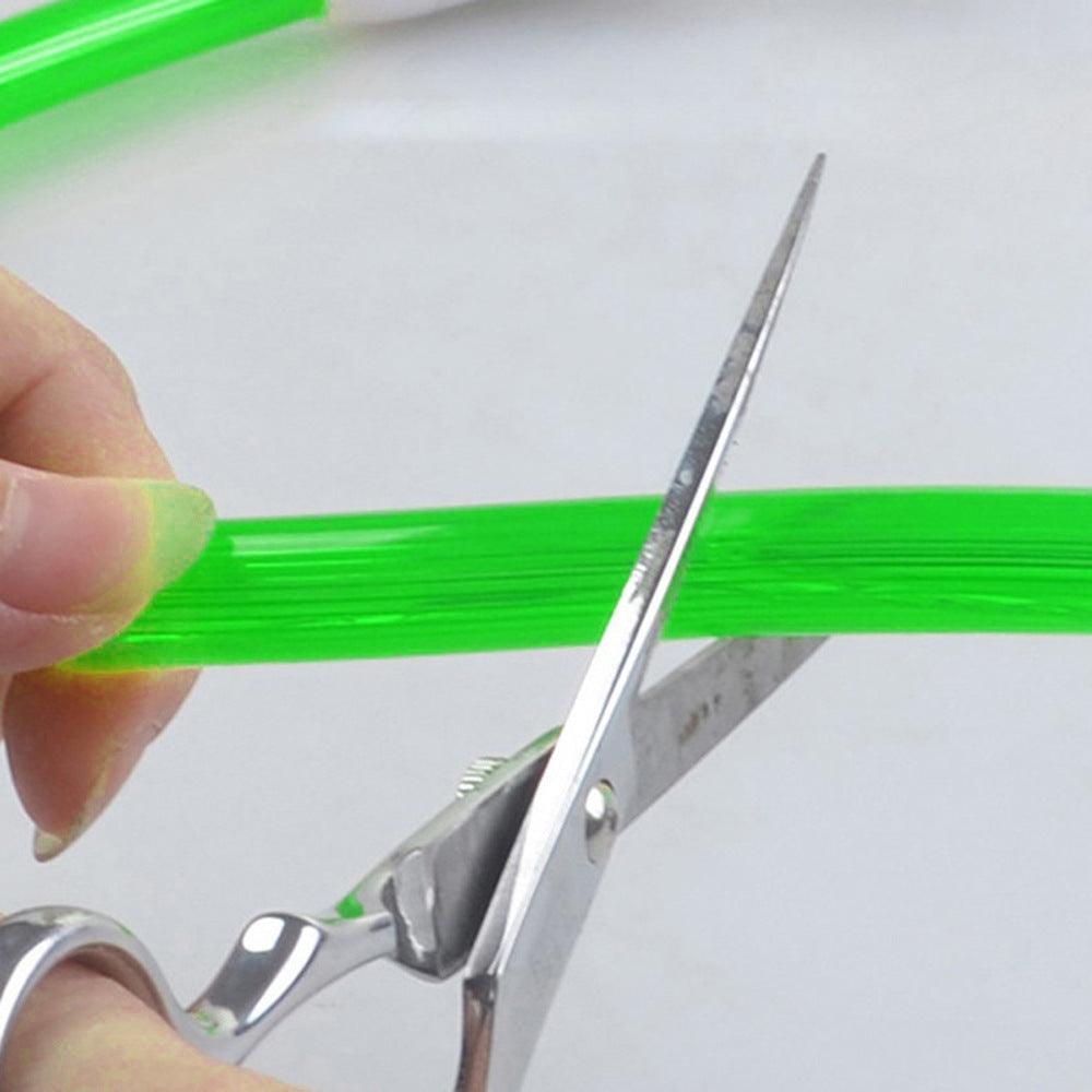 Glow-in-dark green LED pet collar strip, shown near a pair of scissors