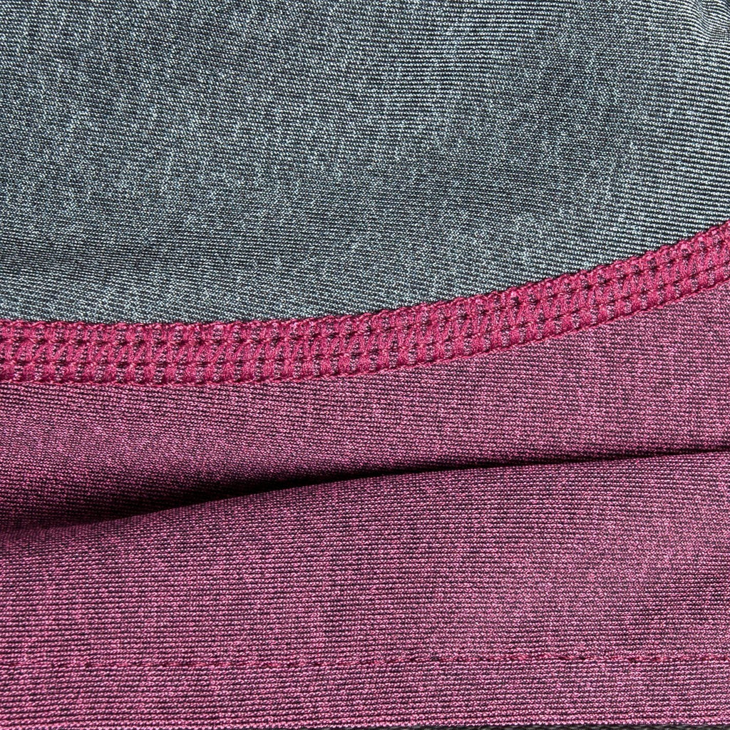 Close-up of burgundy/pink and gray dog tracksuit fabric with stitched seam detail