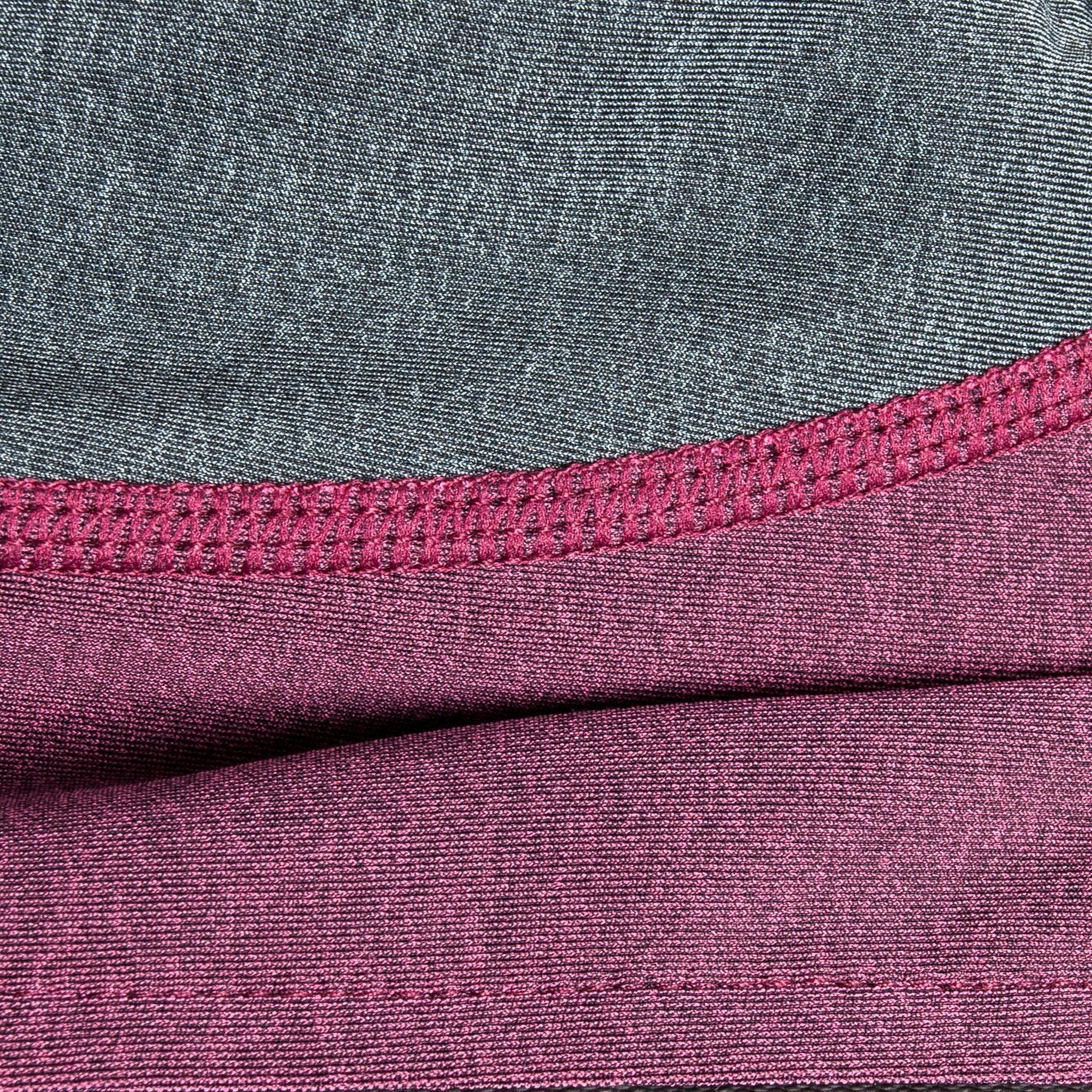 Close-up of burgundy/pink and gray dog tracksuit fabric with stitched seam detail