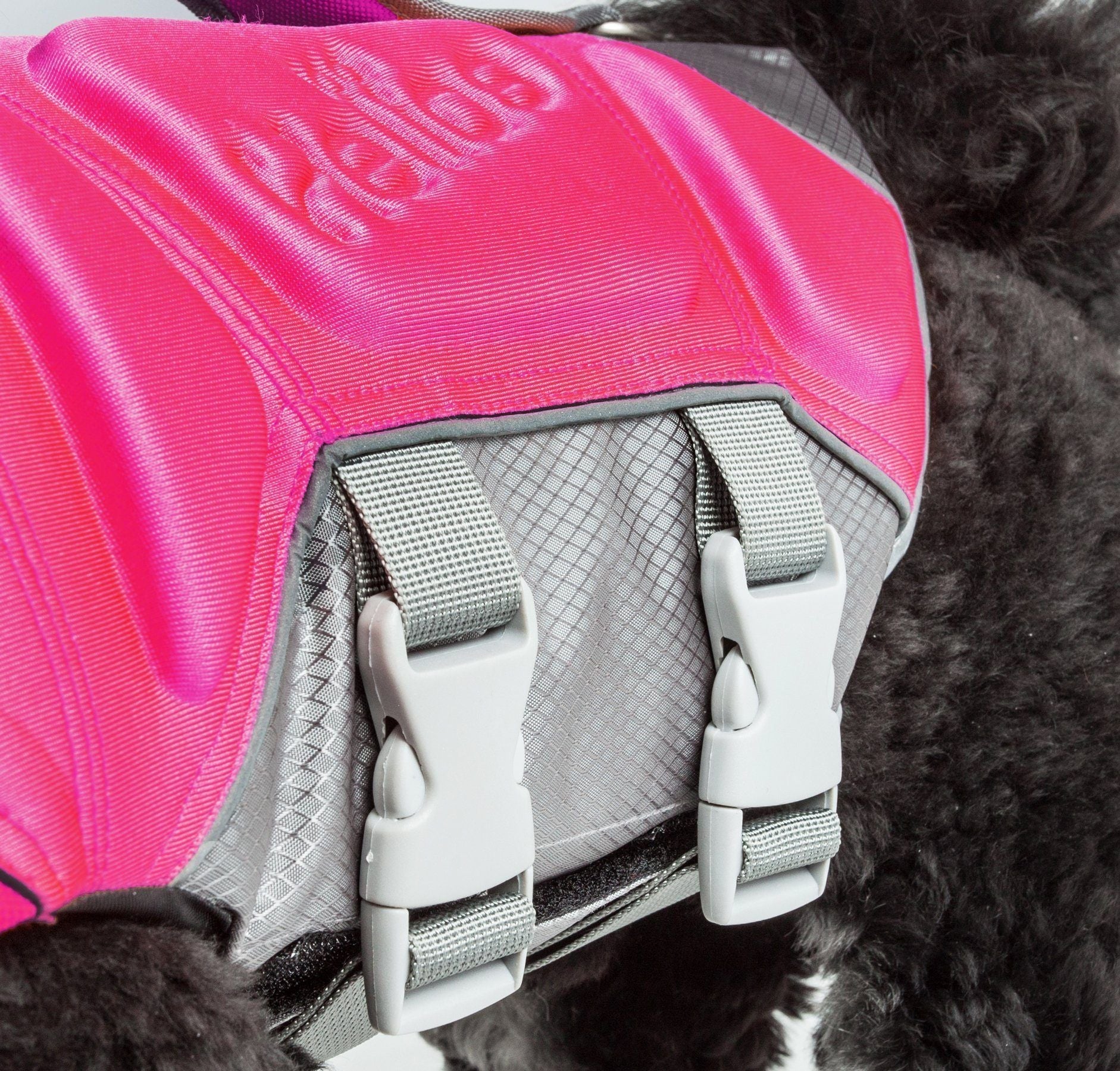 Close-up of pink life jacket vest with gray buckles and textured strap padding