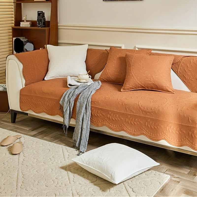 Orange waterproof sofa cover with scalloped edge over arms and seat cushions